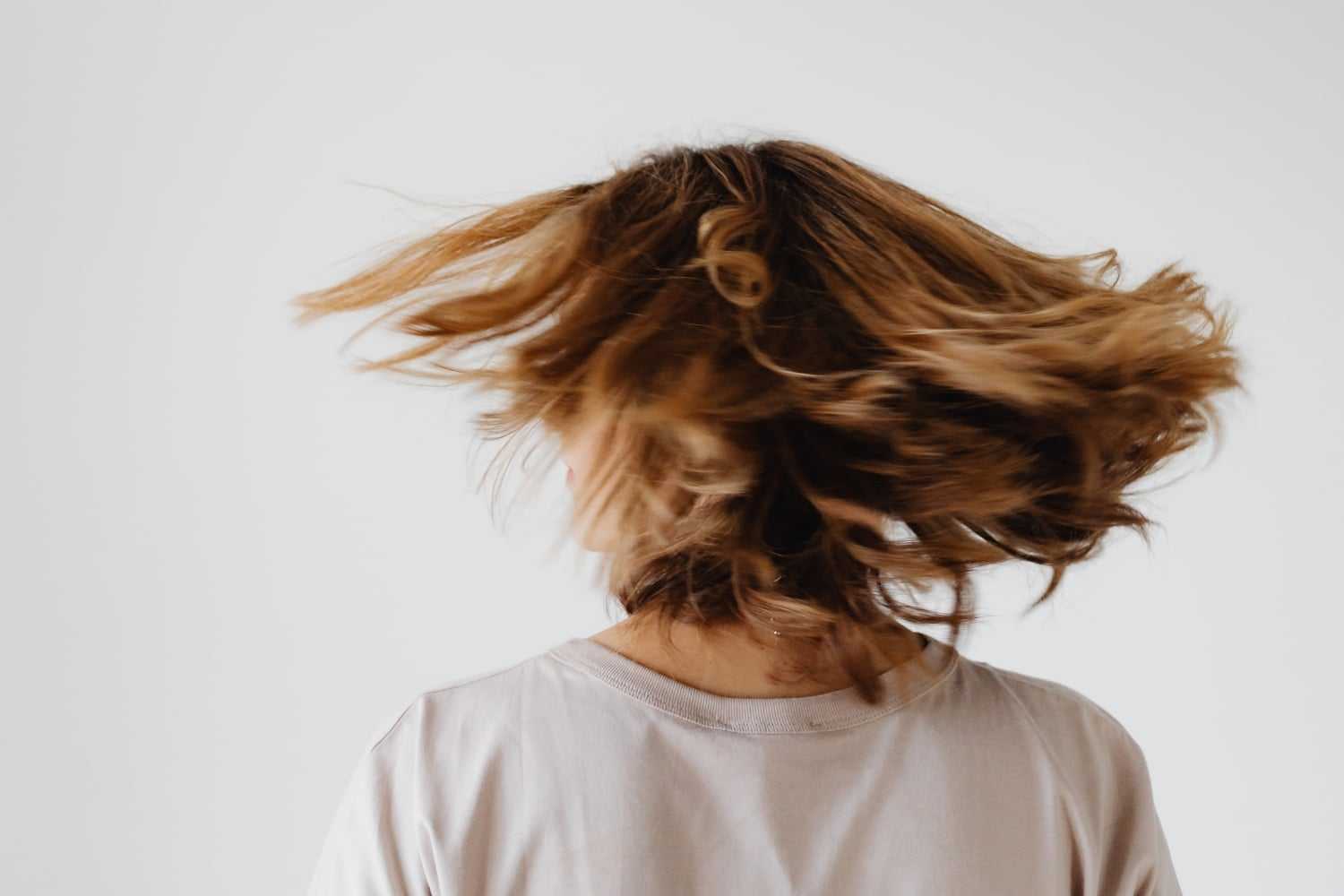 Person with shoulder-length hair spinning around, creating a dynamic motion effect.